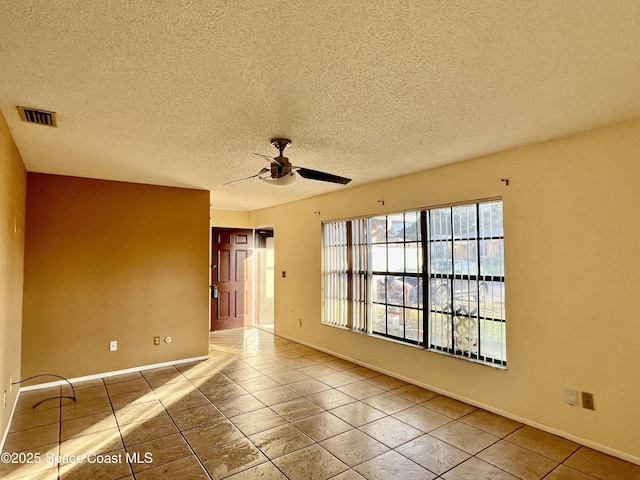 tiled spare room featuring a textured ceiling and ceiling fan