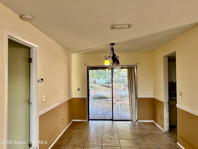 unfurnished dining area with tile patterned flooring and a textured ceiling