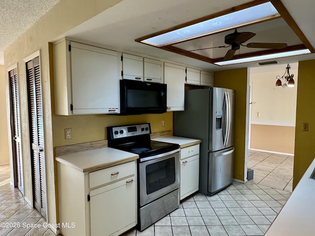 kitchen with stainless steel appliances, white cabinetry, light tile patterned flooring, and decorative light fixtures