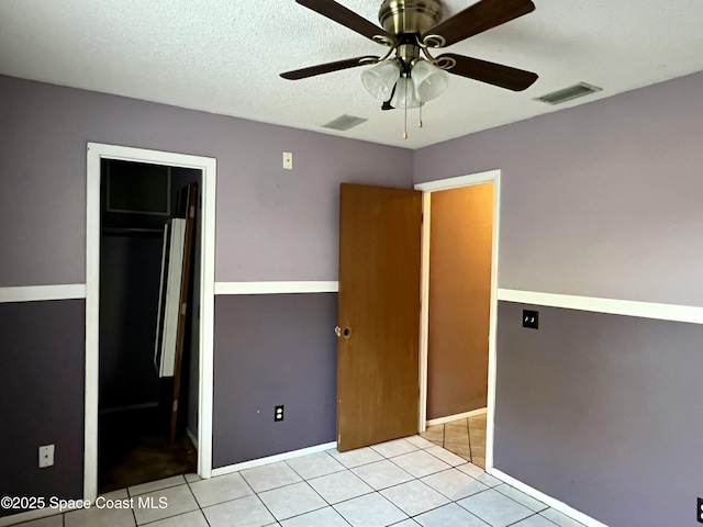 unfurnished bedroom with ceiling fan, a textured ceiling, and light tile patterned floors