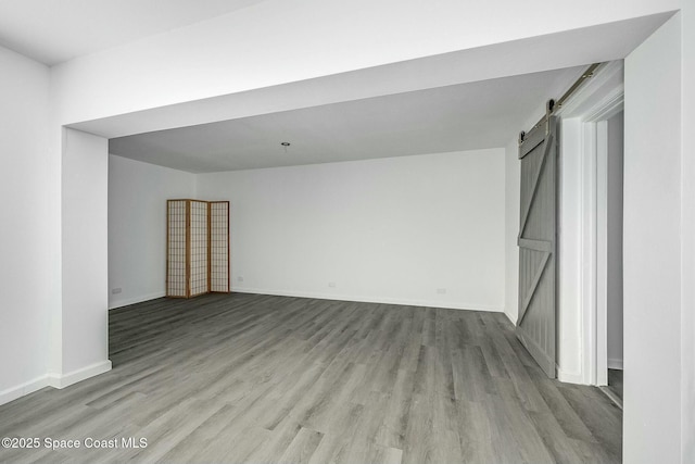 unfurnished room with a barn door and light hardwood / wood-style flooring