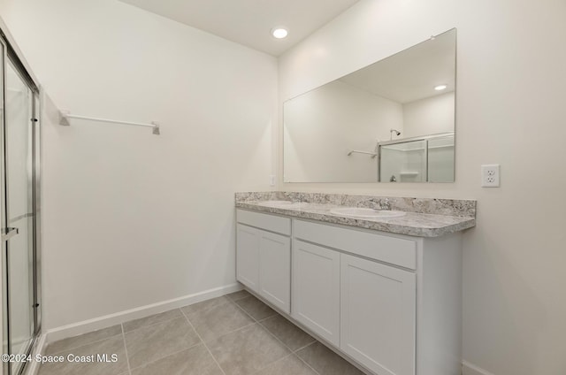 bathroom with a shower with shower door, vanity, and tile patterned flooring