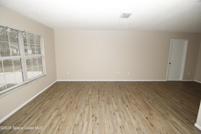 spare room featuring light hardwood / wood-style floors and a textured ceiling