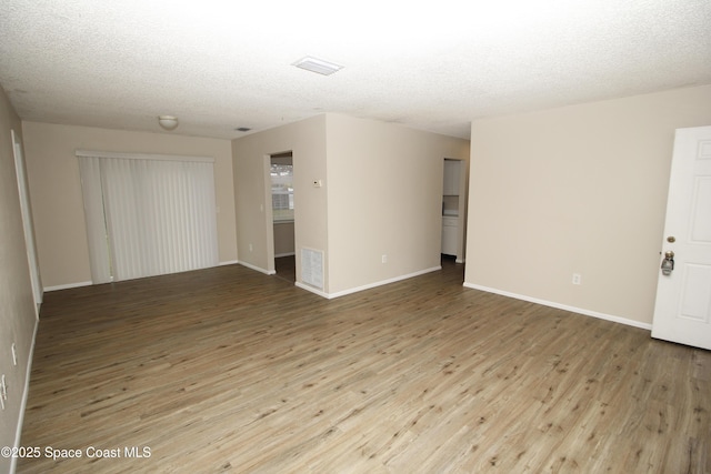 unfurnished room featuring light hardwood / wood-style floors and a textured ceiling