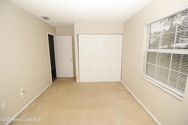 unfurnished bedroom with a closet and light carpet