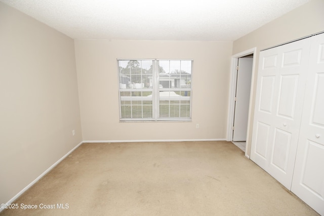 unfurnished bedroom featuring a closet, a textured ceiling, and light carpet