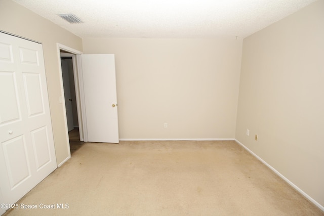 empty room with a textured ceiling and light carpet