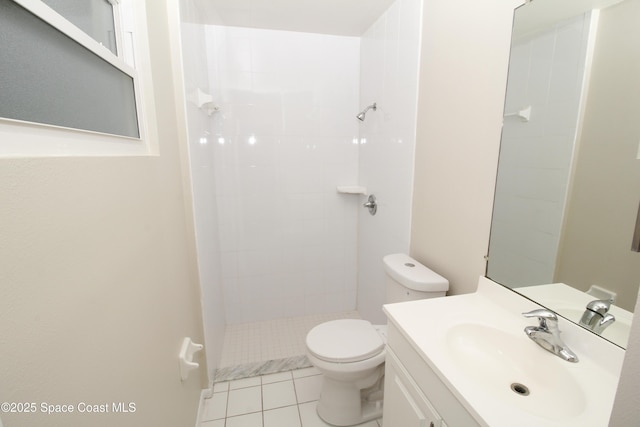 bathroom featuring toilet, vanity, a tile shower, and tile patterned flooring