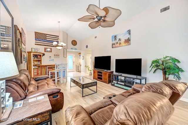 living room featuring vaulted ceiling, ceiling fan with notable chandelier, and light hardwood / wood-style flooring