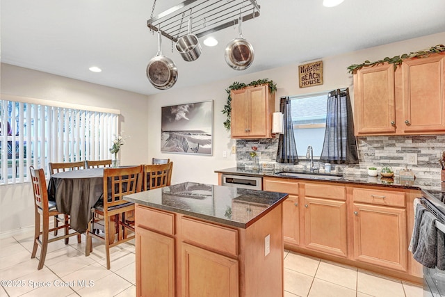 kitchen featuring sink, backsplash, dark stone counters, and a kitchen island