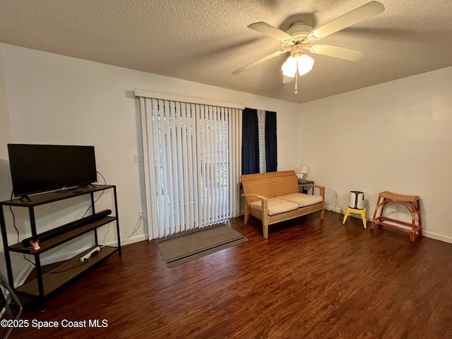 living area with a textured ceiling, dark wood-type flooring, and ceiling fan