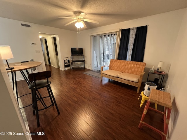 living room featuring ceiling fan, dark hardwood / wood-style flooring, and a textured ceiling