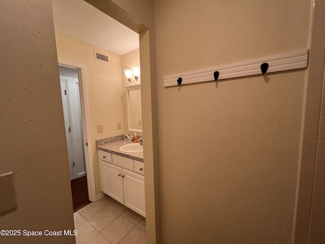 bathroom featuring a textured ceiling, vanity, and tile patterned flooring