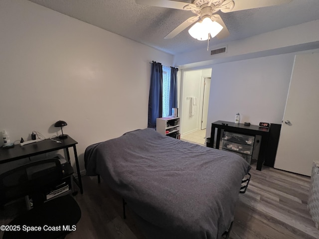 bedroom with a textured ceiling, ceiling fan, and hardwood / wood-style flooring