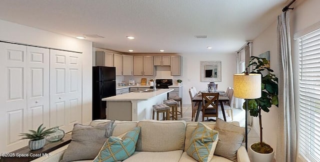 kitchen featuring black refrigerator, gray cabinetry, sink, and a kitchen island