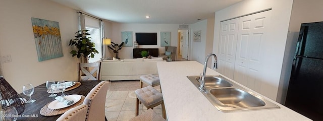 kitchen featuring sink, light tile patterned floors, and black fridge