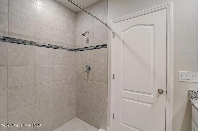 bathroom with tiled shower and vanity