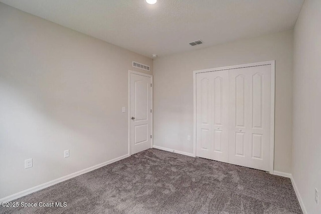 unfurnished bedroom with a closet and dark carpet