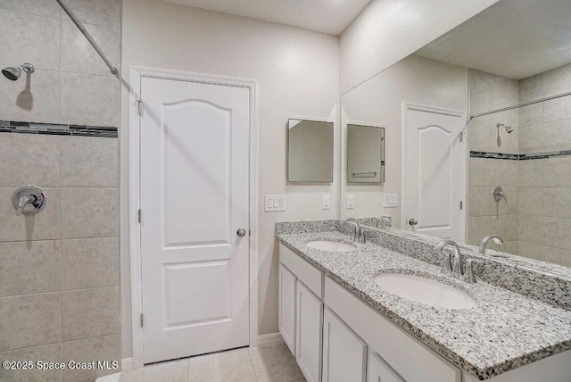 bathroom featuring tiled shower, vanity, and tile patterned flooring