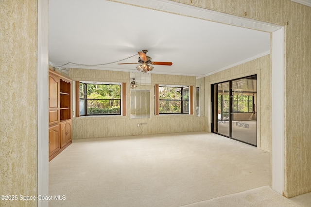 unfurnished room featuring ornamental molding, light carpet, and ceiling fan