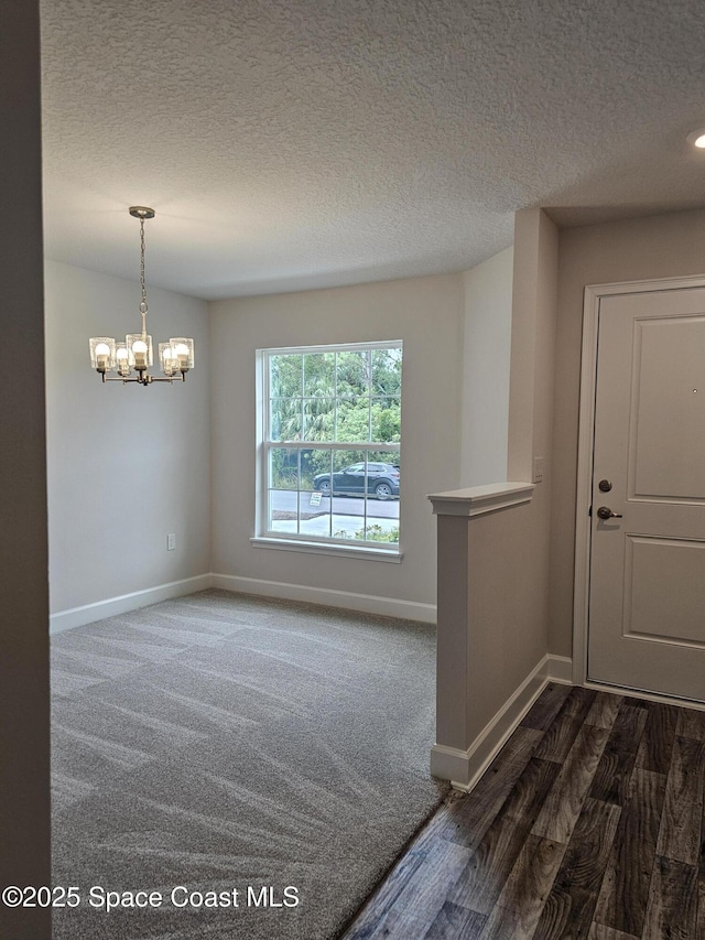 3317 Fitzpatrick Ave SW, Palm Bay, FL 32908 - empty room with a chandelier, a textured ceiling, baseboards, and dark wood-style flooring
