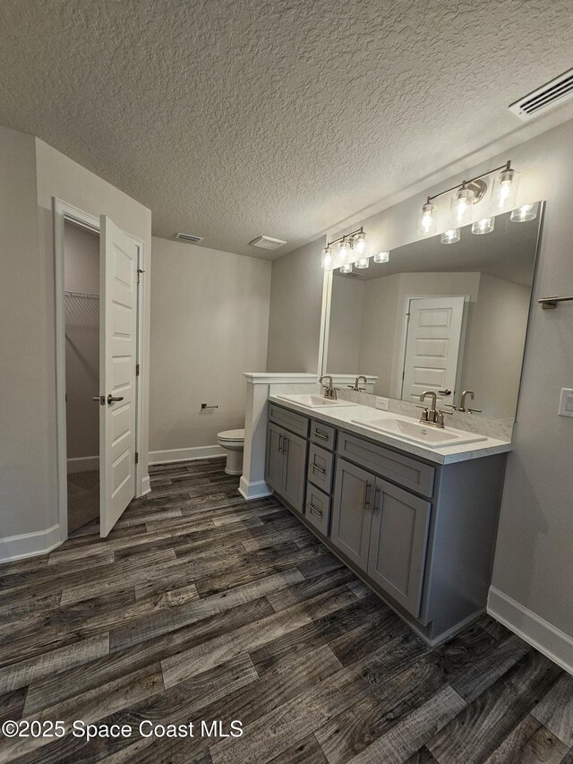 3317 Fitzpatrick Ave SW, Palm Bay, FL 32908 - full bath featuring wood finished floors, double vanity, baseboards, toilet, and a textured ceiling
