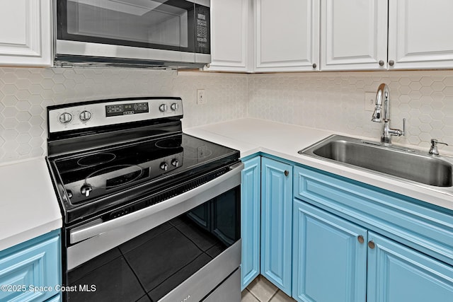 kitchen with appliances with stainless steel finishes, white cabinets, blue cabinetry, and sink