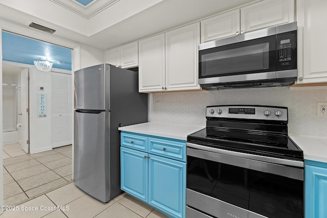 kitchen with white cabinetry, stainless steel appliances, blue cabinetry, ornamental molding, and light tile patterned floors