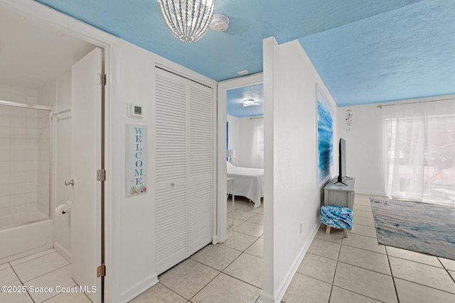 hall with a textured ceiling, light tile patterned floors, and a chandelier