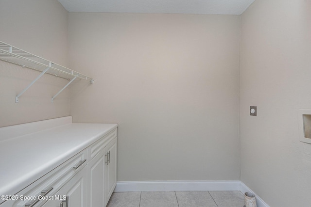 laundry area featuring cabinets, electric dryer hookup, and light tile patterned floors