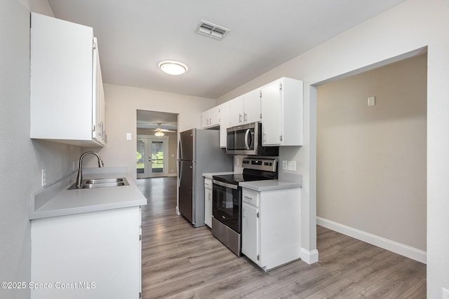 kitchen featuring appliances with stainless steel finishes, french doors, white cabinetry, sink, and light hardwood / wood-style flooring