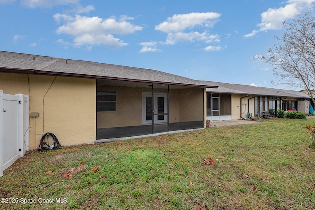 rear view of property featuring a lawn and a sunroom