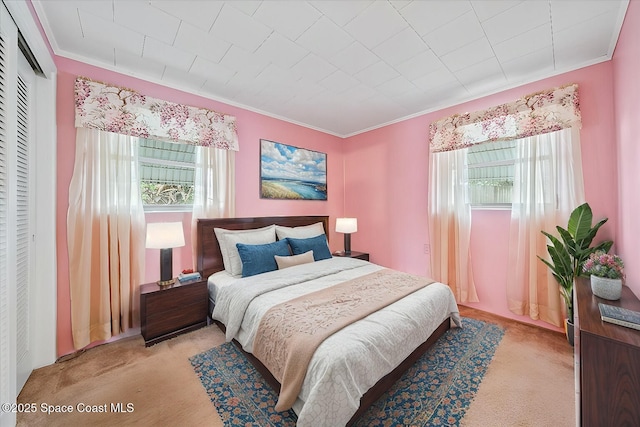 carpeted bedroom featuring multiple windows, crown molding, and a closet