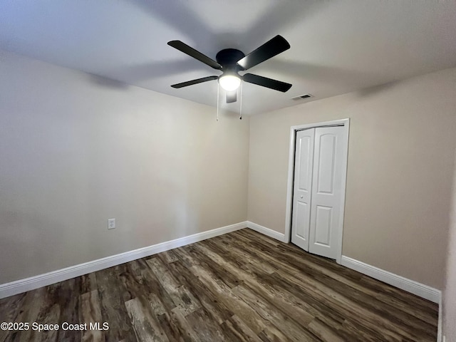 unfurnished bedroom featuring dark wood-type flooring, ceiling fan, and a closet