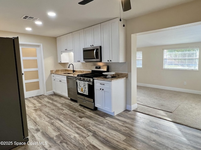 kitchen with sink, white cabinets, ceiling fan, light hardwood / wood-style floors, and stainless steel appliances