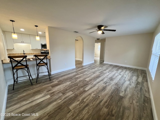 unfurnished living room with sink, dark wood-type flooring, and ceiling fan