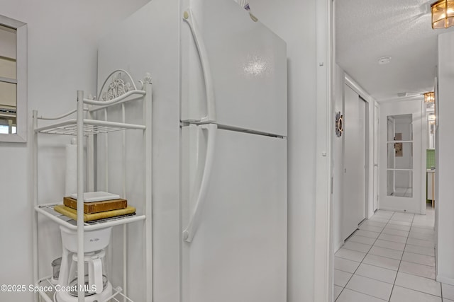 kitchen with white fridge, light tile patterned floors, and a textured ceiling