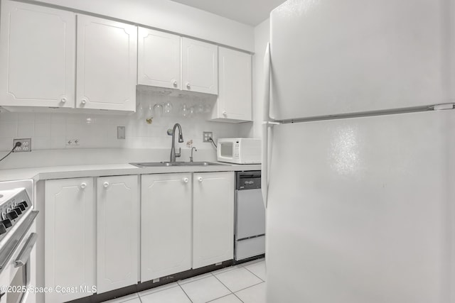 kitchen with white appliances, light tile patterned floors, white cabinets, and a sink