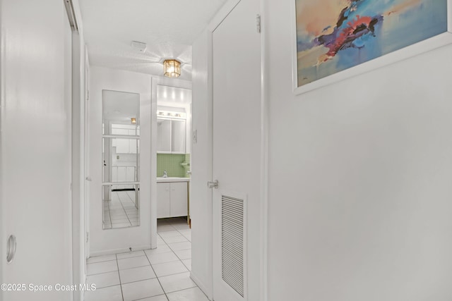 corridor with visible vents, a textured ceiling, and light tile patterned floors