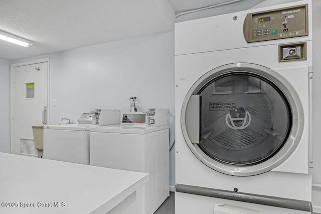 clothes washing area featuring separate washer and dryer and a textured ceiling