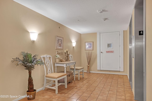 corridor with a textured ceiling, light tile patterned floors, and baseboards