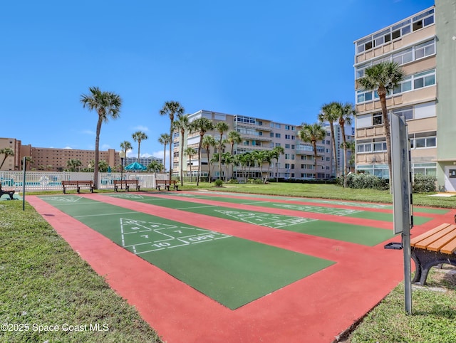 view of home's community featuring shuffleboard, fence, and a lawn