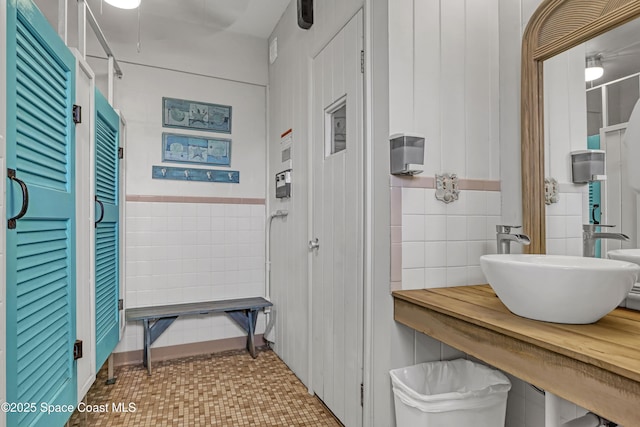 mudroom featuring a sink and tile walls