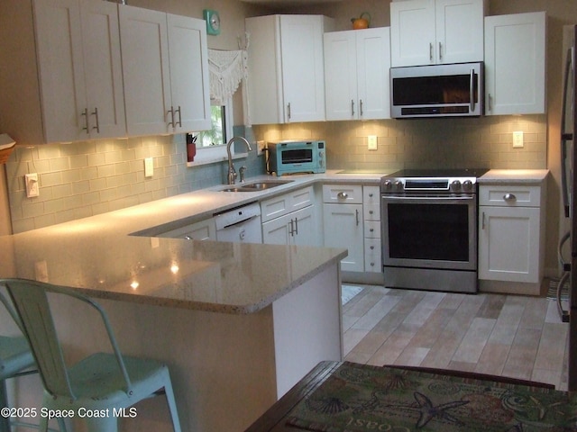 kitchen featuring sink, white cabinetry, appliances with stainless steel finishes, and a kitchen breakfast bar