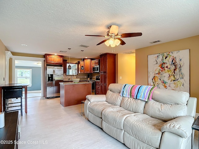 living room with a textured ceiling and ceiling fan