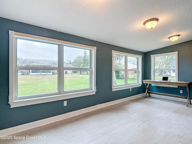 unfurnished office with vaulted ceiling and a textured ceiling