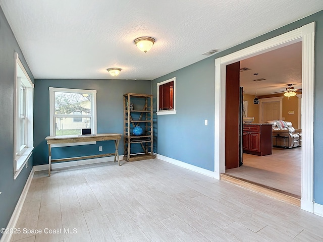 interior space featuring ceiling fan, a textured ceiling, and light hardwood / wood-style floors