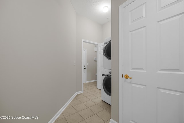 washroom with stacked washer / drying machine, a textured ceiling, and light tile patterned flooring