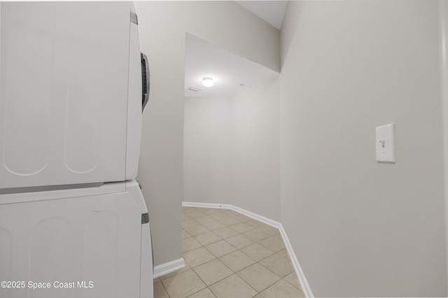 washroom with stacked washer and dryer and light tile patterned floors