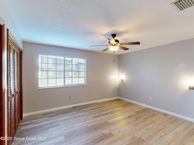 unfurnished bedroom with light wood-type flooring, ceiling fan, and a closet